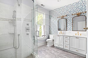A bathroom with gold faucets and a blue wallpaper.