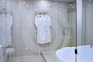 The bathroom has white cotton bathrobes. Photo through a glass partition. Copy of the space