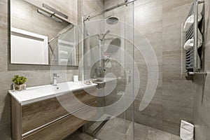 Bathroom with imitation marble tiles, shower cabin with sliding glass doors,