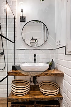 Bathroom interior with black frames, round mirror and classic white tiles