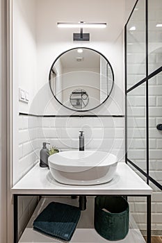Bathroom interior with black frames, round mirror and classic white tiles