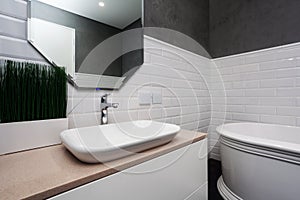 Bathroom interior. Bright bathroom with new tiles. New washbasin, white sink and large mirror.