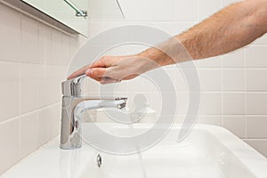 Bathroom interior. Bright bathroom with new tiles. New washbasin, white sink and large mirror. Hand open chrom water tap. photo