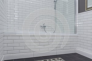 Bathroom interior close-up. The walls are painted gray, covered with decorative ceramic tiles with white glossy bricks.