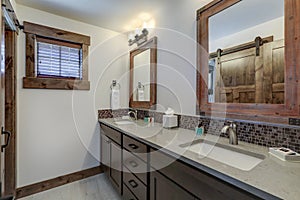 Bathroom interior with grey quarts countertop, two mirrors and barn style doors