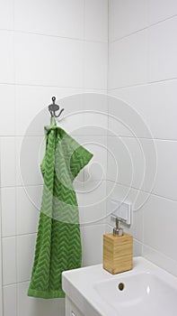 Bathroom interior in light colors with sink, bamboo soap dispenser and green towel