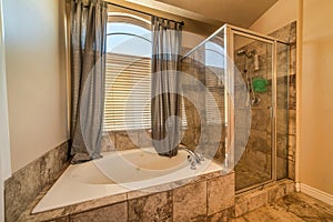 Bathroom interior with round built in bathtub shower stall and warm toned tiles