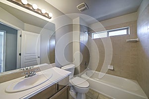 Bathroom interior with single vanity sink and bathtub shower unit with ceramic tiles surround