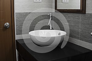 Bathroom interior with white round sink and chrome faucet in a modern bathroom.