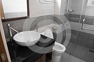Bathroom interior with white round sink and chrome faucet in a modern bathroom with a toilet and shower. Water flowing