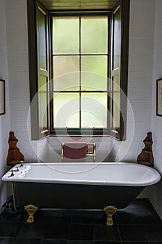 Bathroom with a large antique clawfoot tub underneath a tall window