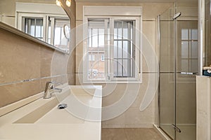 Bathroom with marble sink cabinet, shower cabin with folding glass door and window with bars