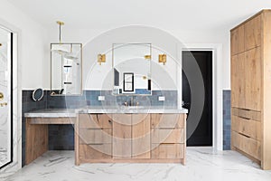 A bathroom with natural wood cabinets and blue tiles.