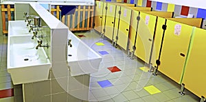 Bathroom of a nursery with white sinks and yellow toilet doors