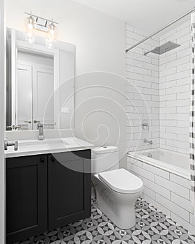 A bathroom with a pattern tile flooring and subway tile shower.