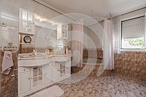 Bathroom with pink marble sink on white wooden cabinets