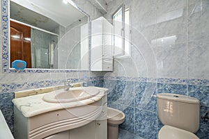 Bathroom with porcelain sink, wall-mounted mirror with valance, and half-height blue tiles