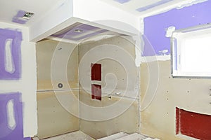 Bathroom remodel progresses as drywall is smoothed, covering seams and screws with tape