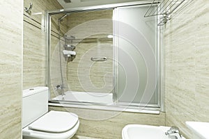 Bathroom with shower cabin with chrome screen, marble tiling