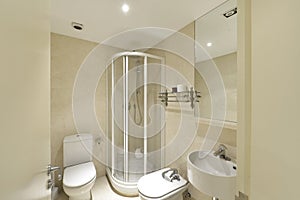 Bathroom with shower cabin with transparent partitions, light marble tiling, frameless mirror and small white porcelain designer