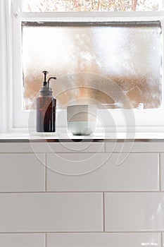 Bathroom soap dispenser and pot on window ledge with negative sp