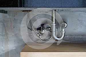 Bathroom steel sink pipes, trap and drain on concrete wall