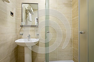 Bathroom,tiles and bright colors of broom, shower with frosted doors,mirror above the sink. Hanging a towel over the toilet on a h