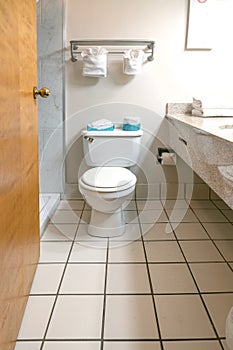 bathroom and toilet are tiled with white tiles and have a large mirror in front of the sink