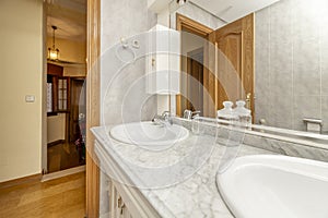 Bathroom with two sinks integrated into the marble countertop and mirror integrated into the white wooden cabinet
