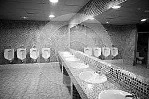 Bathroom urinal in a row with gray tiles photo