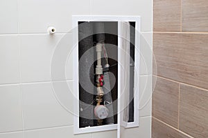 Bathroom wall hatch with pipes and water meter. Transmission of water meter readings
