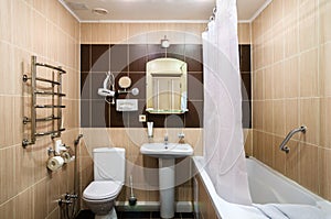 Bathroom in warm colors, with a toilet, a bathtub, a hairdryer, a mirror, a dryer for clothes