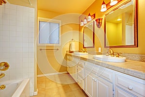 Bathroom with white cabinets and gold walls.