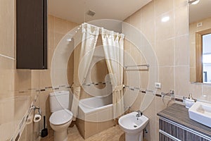 Bathroom with white porcelain fixtures, cream shower curtains, wooden vanity cabinet, and frameless wall mirror