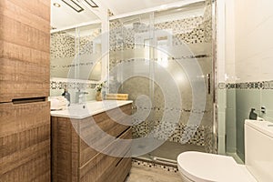 Bathroom with white porcelain sink with large wood-drawer cabinets, frameless mirror and valance on wall, and walk-in shower with