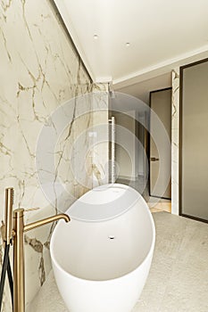 Bathroom with white surface bathtub and brass taps