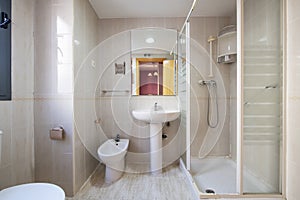 Bathroom with white toilets and a rectangular mirror attached to the wall and a shower cabin with a screen with white edges