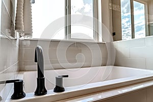 Bathtub with black faucet built in to the bathroom with tile wall and floor