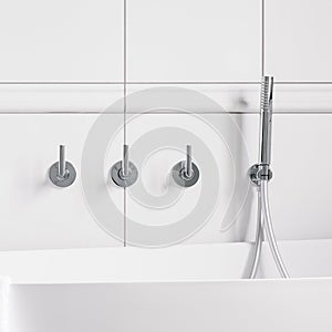 Bathtub faucet in white wall, close-up