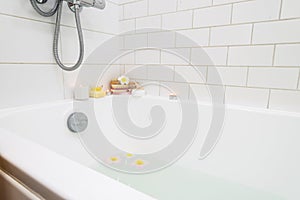 Bathtub with Plumerria Flowers and Inflatable Flamingo Toy Ring with Drink Bamboo Face Brush Home SPA Concept Relax