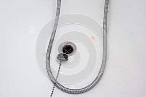 Bathtub rubber plug on a chain next to shower cord close up shot top view