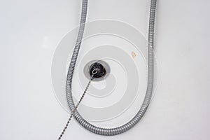 Bathtub rubber plug on a chain next to shower cord close up shot top view