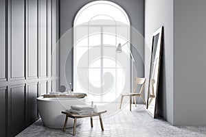 Bathtub with water in grey bathroom interior