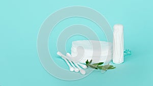 Batons and cotton buds for ears and makeup remover made of cotton on a turquoise background with small white flowers. feminine