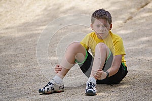 Battered boy sits on the ground with a scratched face and a sad look