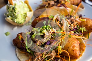 Battered fish tacos topped with slaw and salsa, served with guacamole at a restaurant on the beach