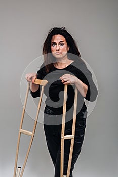 A battered woman in black clothes with casters in her hands on a gray background