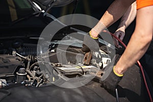 Battery charger and car in auto repair shop,Auto mechanic working in garage. Repair service