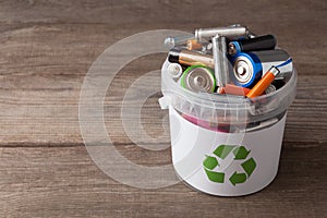 Battery recycle bin with old element on wood table.