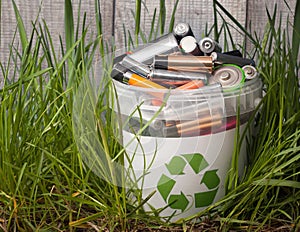 battery recycle bin with old element on wood table in grass